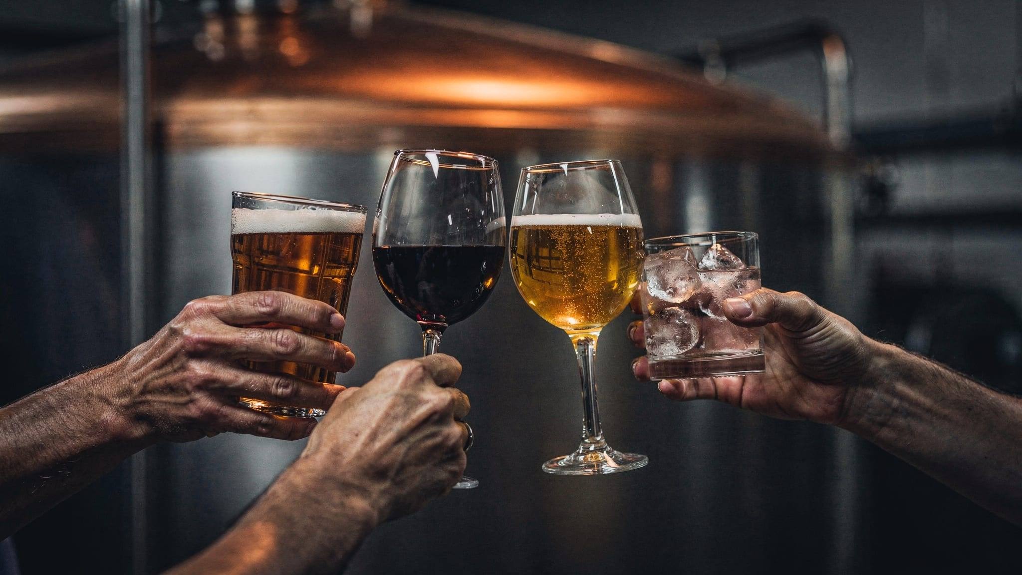 Glasses of beer, wine, cider and spirit raised together in a toast.